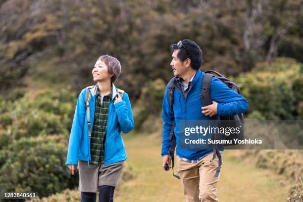 a couple hiking in the mountains in the fall - 夫婦 ストックフォトと画像