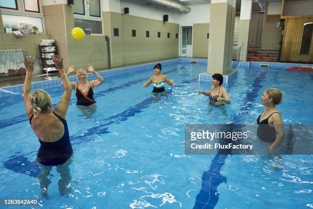 group of joyful modern senior women attending a aqua aerobic class at rehabilitation center - candid volleyball stock pictures, royalty-free photos & images