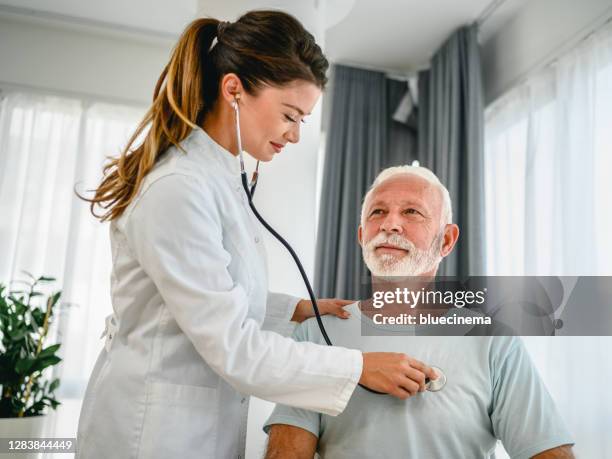 vrouwelijke arts die stethoscoop gebruikt die aan hogere patiënten luistert die ademen - long beard stockfoto's en -beelden