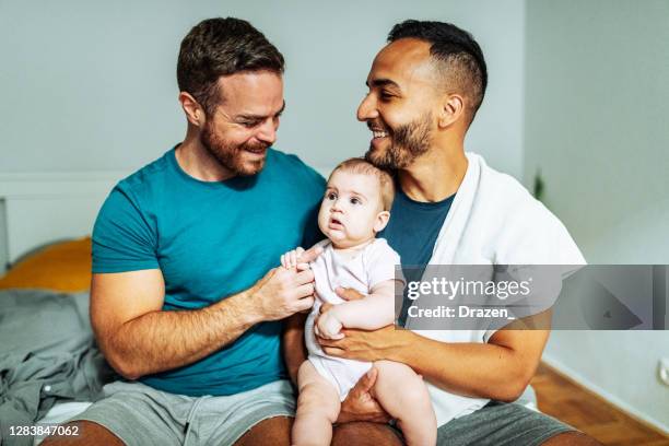 sonriente pareja gay con bebé caucásico adoptado - persona gay fotografías e imágenes de stock