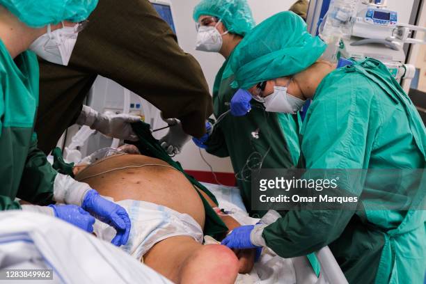Medical personnel wear protective suits, masks, gloves and face shields as they accommodate a new critical patient at the ICU of Krakow University...