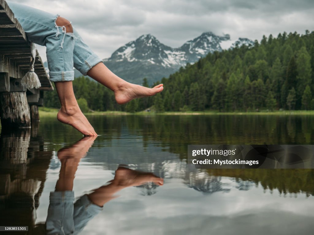 Feet dangling from lake pier