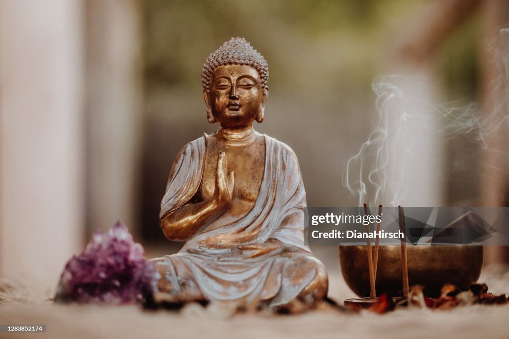 Nahaufnahme einer Buddha-Figur und rauchigen Weihrauch mit Gong und Amethyst