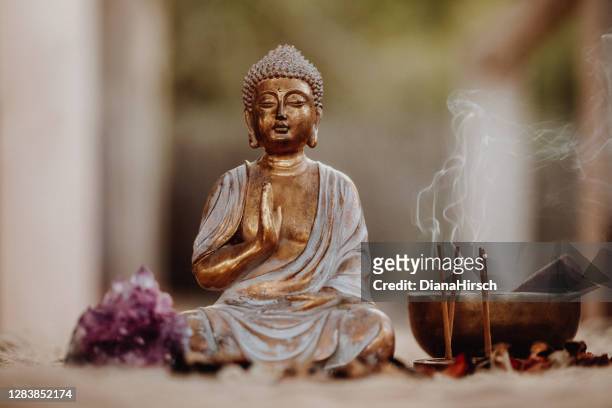 nahaufnahme einer buddha-figur und rauchigen weihrauch mit gong und amethyst - spirituality stock-fotos und bilder