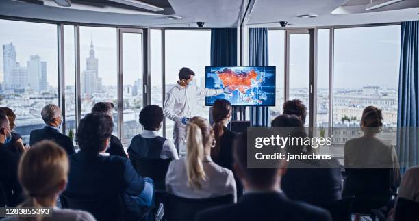 coronavirus medicine symposium. young, asian doctor presenting map of disease outbreaks in asia - to assemble world stock pictures, royalty-free photos & images