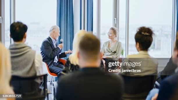 mature businessman giving an interview during a conference. q&a panel - corporate business owner stock pictures, royalty-free photos & images