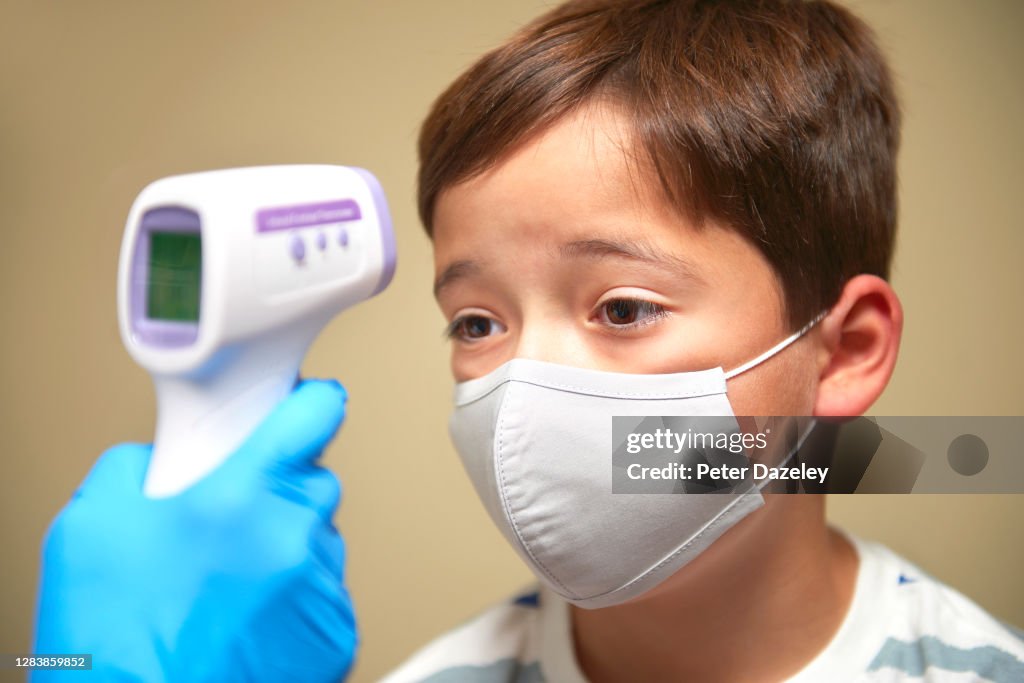 9 year old boy having temperature taken, during covid-19 test