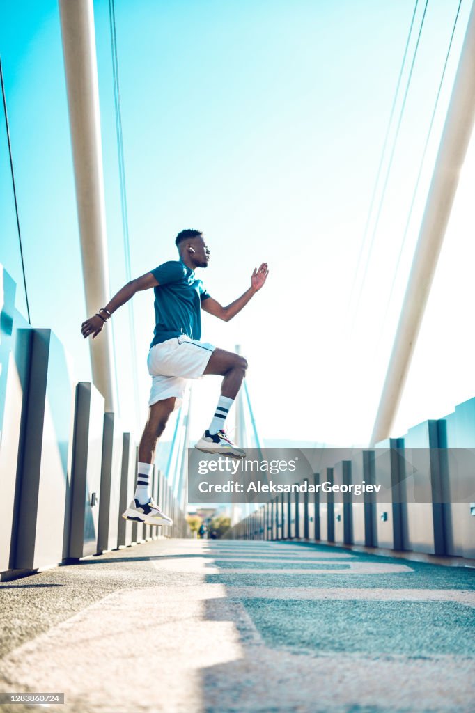 橋��の上でジャンプエクササイズをしているアスレチックアフリカの男性