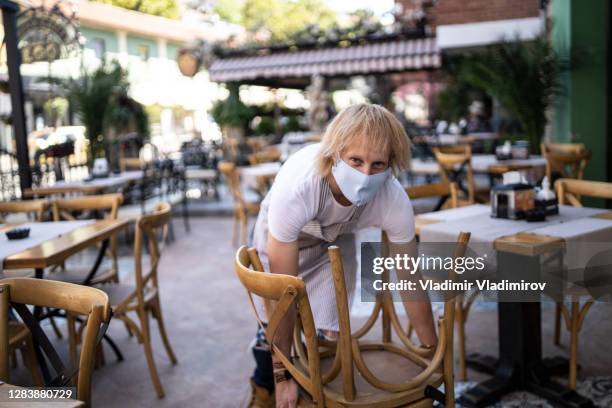 waiter packing away chairs in a restaurant - bulgaria coronavirus stock pictures, royalty-free photos & images