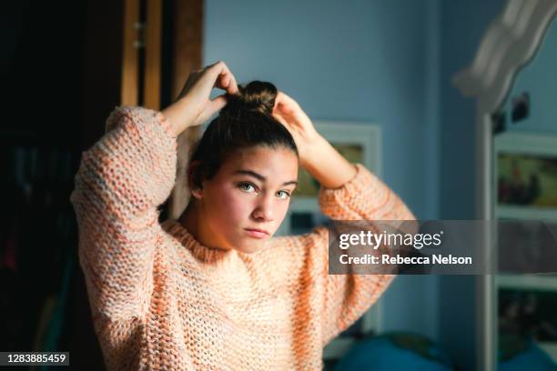 teenage girl putting her hair in a bun - girl in mirror stockfoto's en -beelden