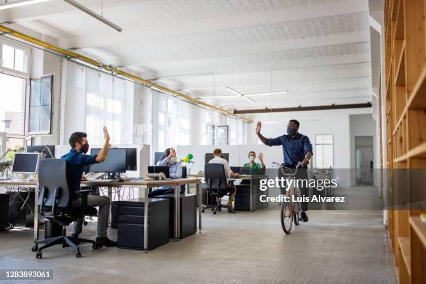 male professional riding cycle in creative office - bike work stockfoto's en -beelden