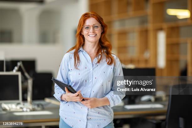 portrait of female executive standing at office - dyed red hair stock-fotos und bilder