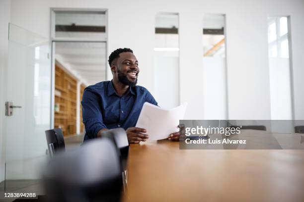 businessman sitting in conference room and smiling - businessman sitting in chair stock-fotos und bilder