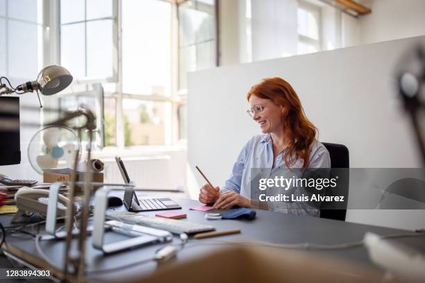 businesswoman having teleconference from her desk - cheveux roux photos et images de collection