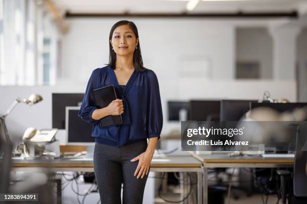 portrait of confident female executive with digital tablet - business woman blue stockfoto's en -beelden