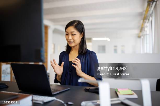 woman having a teleconference at her desk - webinars woman stock pictures, royalty-free photos & images