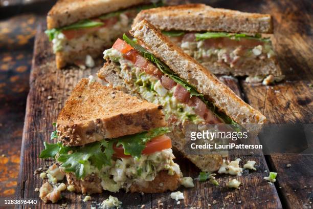 sandwich de ensalada de aguacate y huevo con tocino crujiente, lechuga y tomate - bocadillo de beicon lechuga y tomate fotografías e imágenes de stock