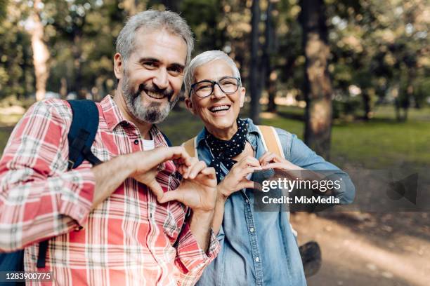 pareja madura en un viaje en la naturaleza mostrando corazones - two hearts fotografías e imágenes de stock