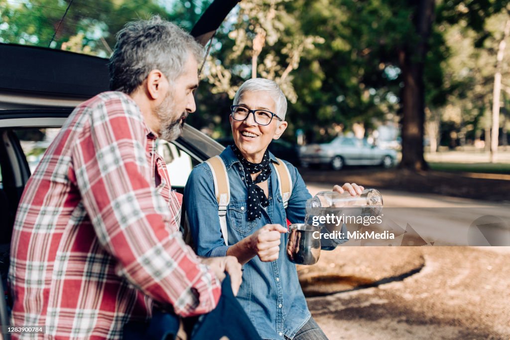 Senior couple on a road trip in the nature taking a break for refreshment