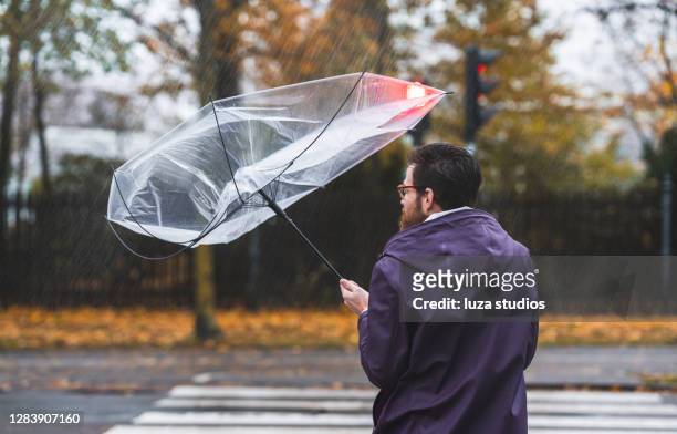regenschirm im wind gefangen - regen stock-fotos und bilder