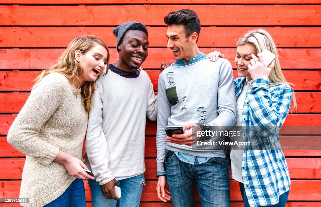 Millenial best friends using smart phone at urban city area - Technology and friendship concept with young happy people sharing stories on social media with mobile smartphone - Bright vivid filter