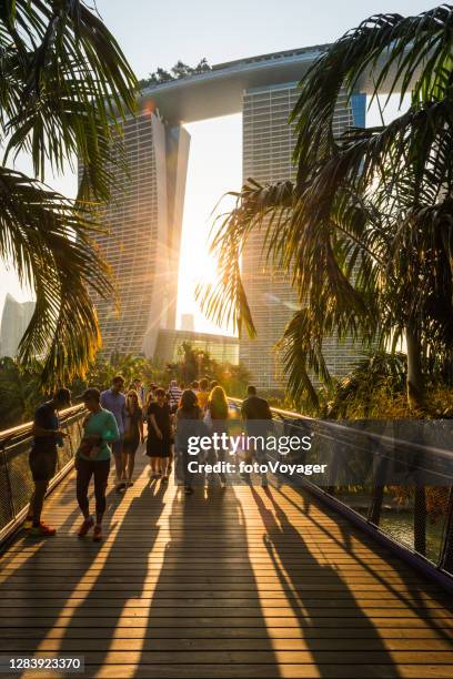 singapore marina bay sands crowds of tourists on boardwalk sunset - marina bay sands stock pictures, royalty-free photos & images