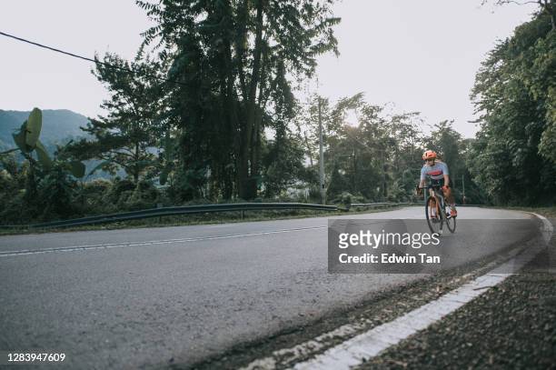 low angle asian chinese woman road bike cyclist sprinting cycling in rural area in the morning