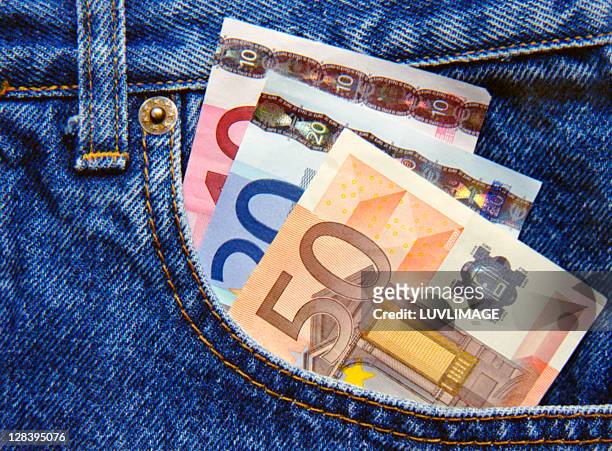 euro in jeans pocket sticking out - pantalon stockfoto's en -beelden
