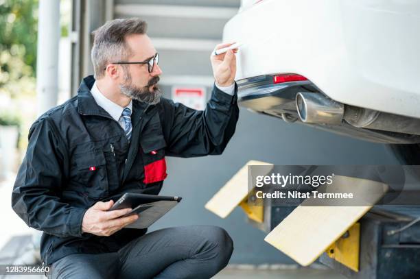 car insurance agent using check mark on car trunk lid and record in the mobile application at auto repair center. car insurance claim process. car damage assessment. business hour 24/7 service coverage. - car insurance agent stock pictures, royalty-free photos & images