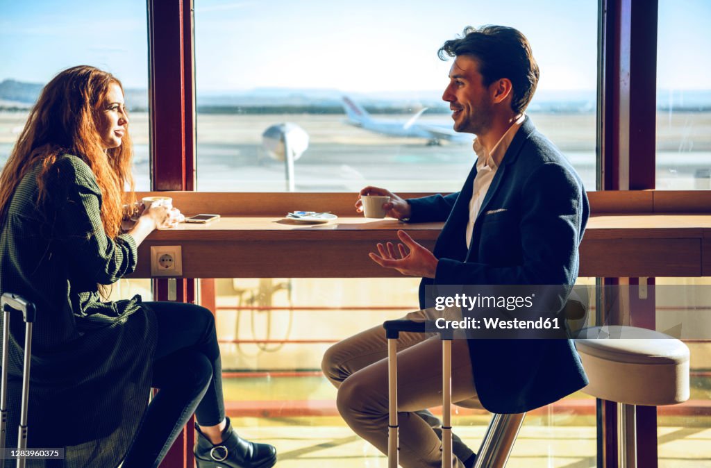 Happy business couple discussing while sitting at airport cafe