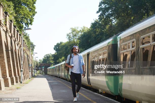 young trendy man walking at railroad station platform during sunny day - train leaving stock pictures, royalty-free photos & images