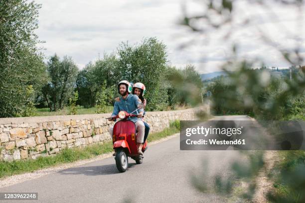 couple enjoying road trip on vespa, tuscany, italy - motorino foto e immagini stock