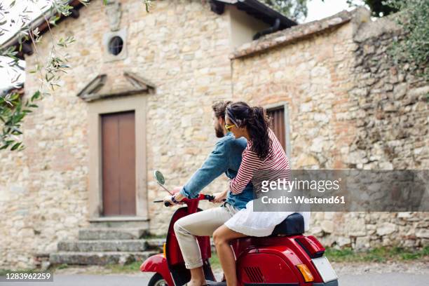 couple enjoying road trip on vespa - italien stock-fotos und bilder