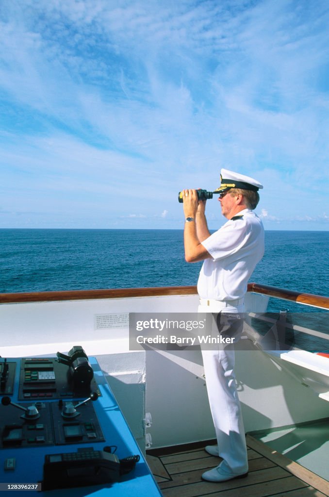 Captain w/ binoculars on bridge of cruise ship