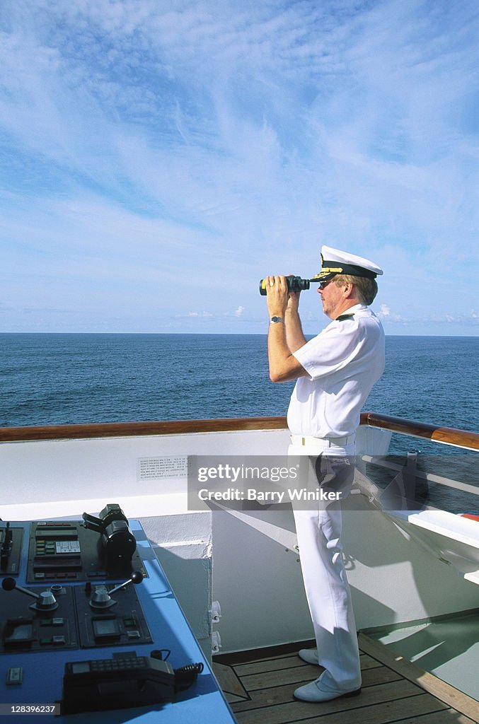 Captain w/ binoculars on bridge of cruise ship