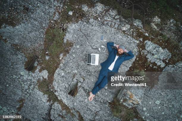aerial view of businessman wearing suit with hands behind head relaxing on land in forest - crazy man computer stock pictures, royalty-free photos & images