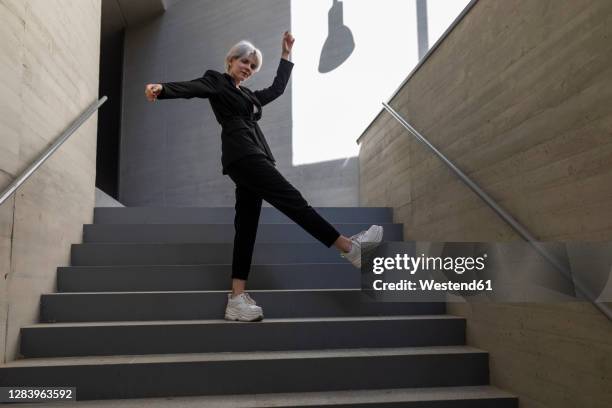 businesswoman wearing elegant suit dancing on steps in building - portrait fashion woman stock-fotos und bilder