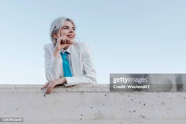 smiling young woman wearing white suit standing by retaining wall against clear sky - women in slips bildbanksfoton och bilder