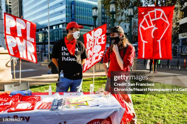 Acosta and Will Shattuc chat behind the East Bay Democratic Socialists of America table during the Defend Our Democracy: Count Every Vote event held...