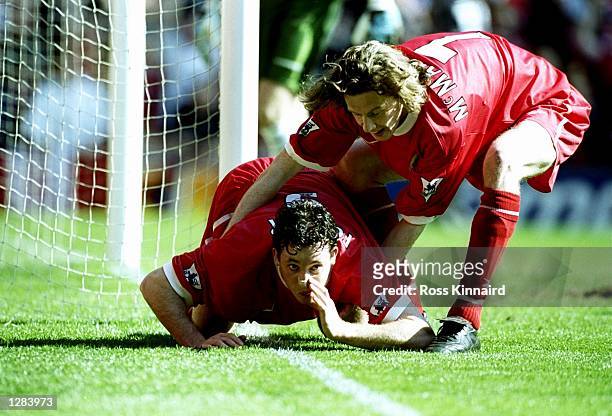 Robbie Fowler of Liverpool is pulled away by team mate Steve McManaman after mimicking cocaine snorting to celebrate his first goal against Everton...