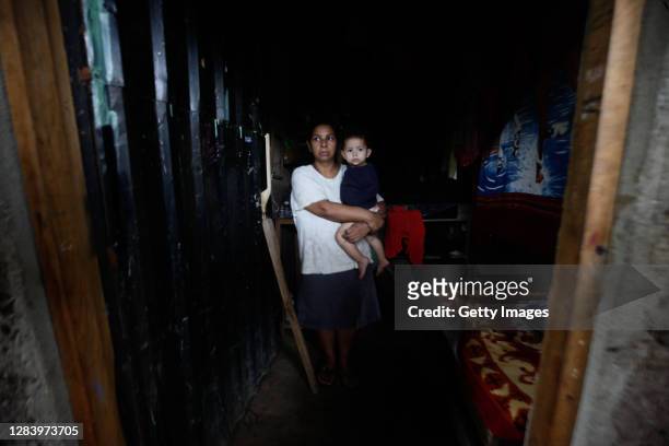 Dulce Liceth Duarte holds her son while workers check her house because of high risk of a landslide after the flooding of Rio Chiquito due to the...