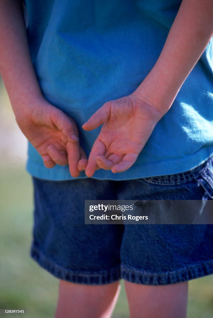 Boy with fingers crossed behind back