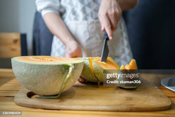 cutting up the  japanese melon fruit on wooden table with copyspace - gladde meloen stockfoto's en -beelden