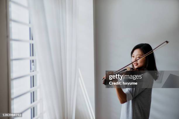 an asian chinese woman practicing violin at home - beautiful woman violinist stock pictures, royalty-free photos & images