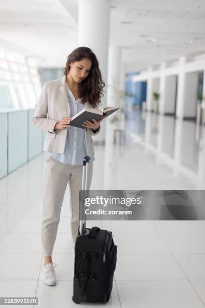 junge geschäftsfrau wartet am leeren terminal mit koffer und buch - arab businesswoman with books stock-fotos und bilder