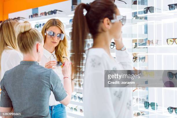 amis essayant des lunettes de soleil - duty free photos et images de collection