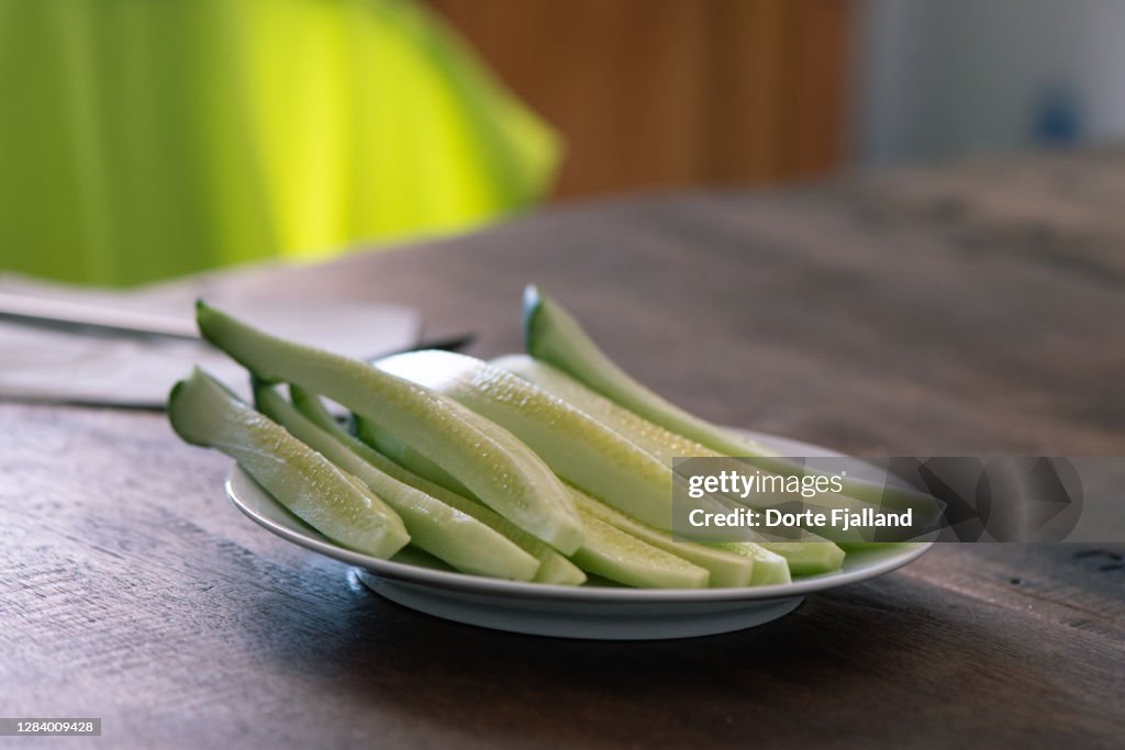 Peeled cucumber sticks on a plate on a wooden table