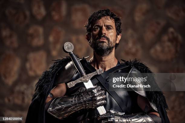 chevalier médiéval mûr de fantaisie mûr dévot retenant son épée devant lui tandis qu’il prie - acteur photos et images de collection