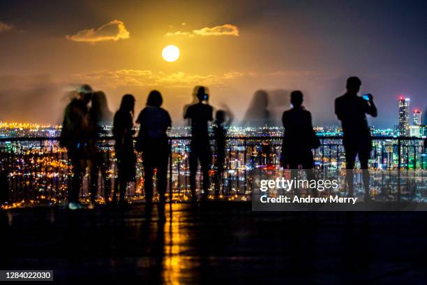 city at night with people looking at supermoon - supermoon 個照片及圖片檔