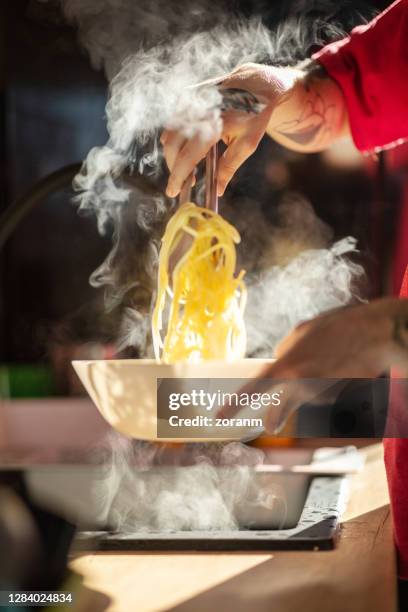 usando pinças para derramar espaguete fumegante na tigela - pinça utensílio de servir - fotografias e filmes do acervo
